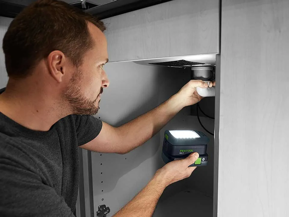 En mand belyser tilslutningen af en håndvask med SYSLITE KAL 2