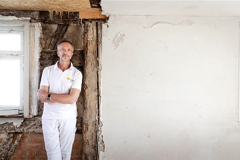 Manfred Schuler, malermester og restaurator foran væggen i det bindingsværkshus, der skal restaureres