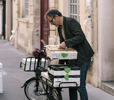 Efter udført arbejde pakker den usædvanlige snedker sit værksted sammen og begiver sig igen af sted på cyklen gennem Paris' gader.